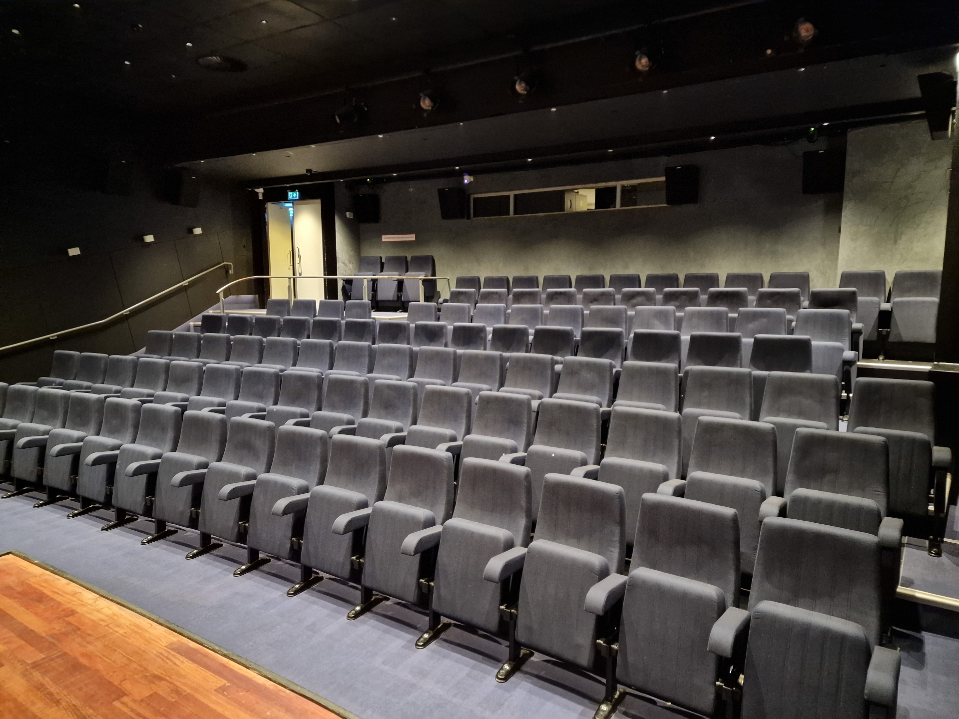 Donkergrijze theaterstoelen op oplopende tribune in Theater de Leest in Waalwijk — professioneel gereinigd op locatie